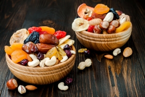 Mix of dried fruits and nuts on dark wood background with copy space. Symbols of judaic holiday Tu Bishvat